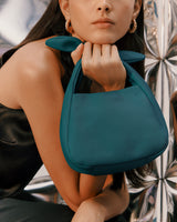 Person holding a handbag with shiny background.