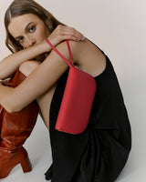 Person seated with a handbag on shoulder, wearing a dress and knee-high boots.