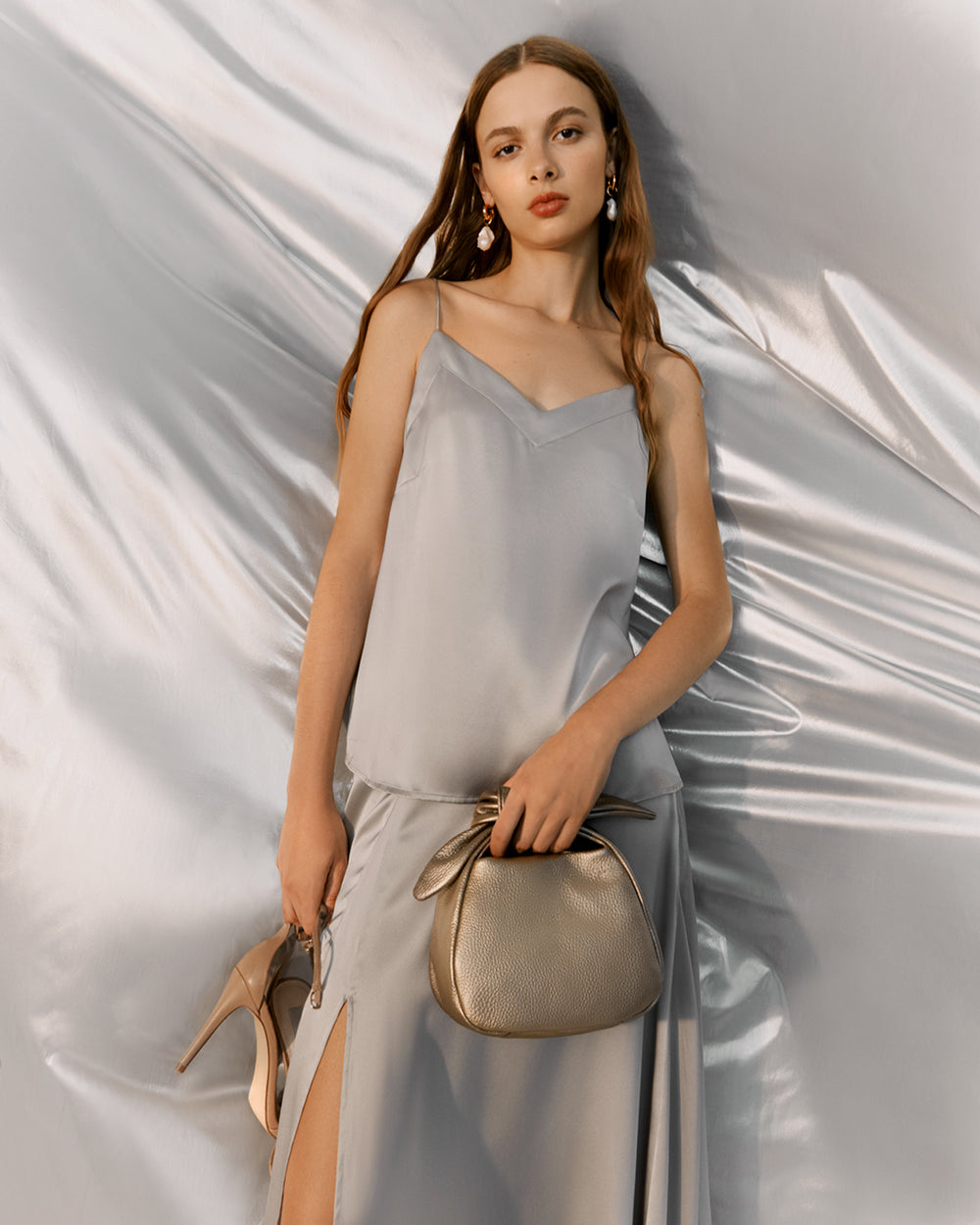 Woman standing with a handbag and high heels.