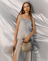 Woman standing with a handbag and high heels.