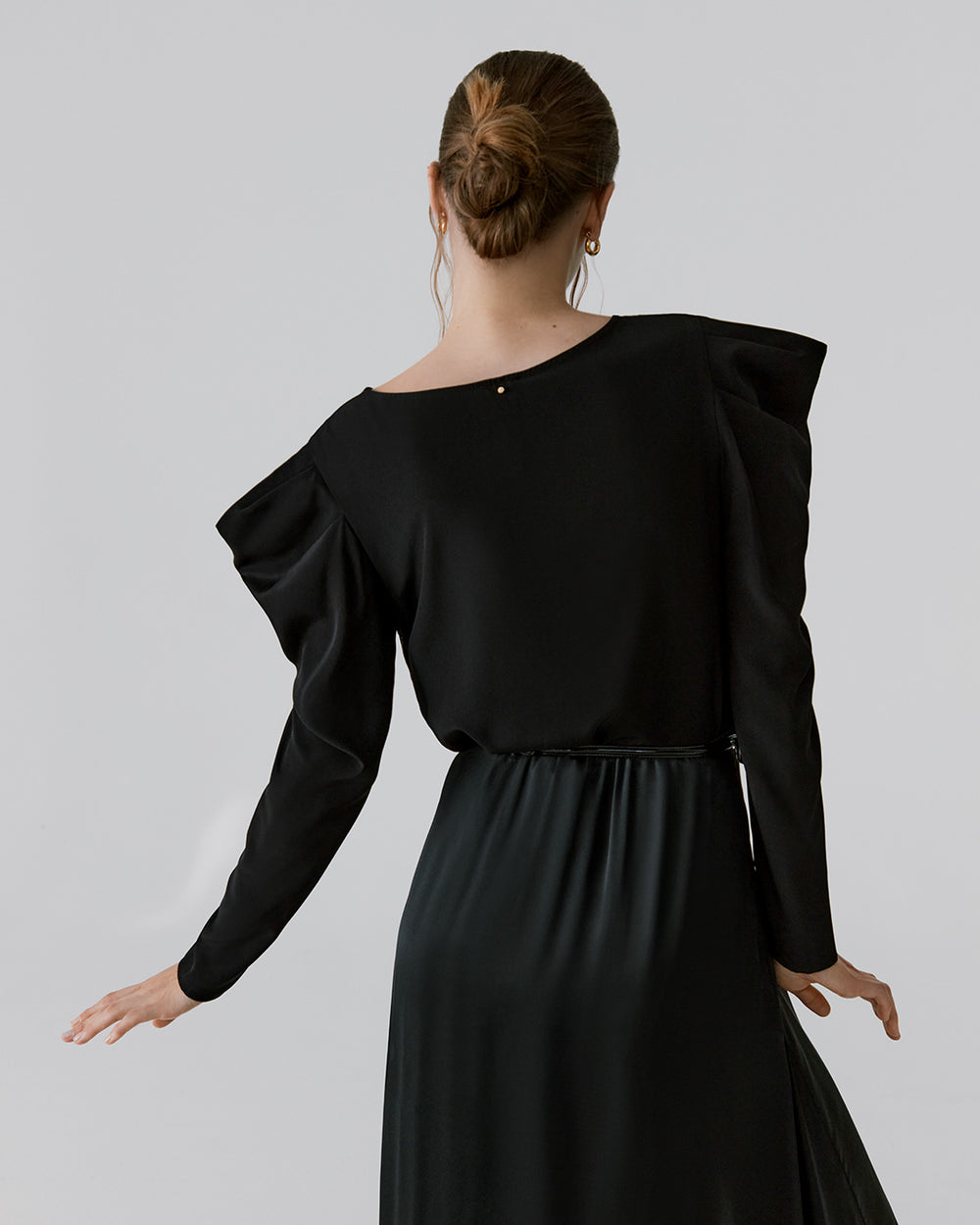 Woman seen from behind, wearing a long-sleeve dress with a gathered waist.