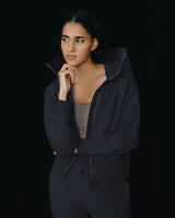 Woman in hoodie looking thoughtful with hand on chin