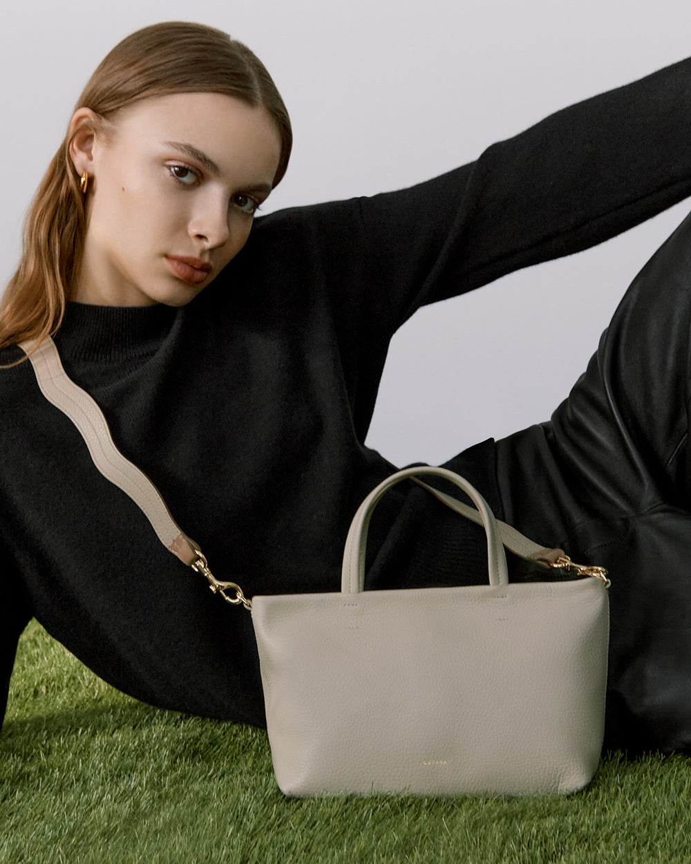Woman lying on grass next to a handbag