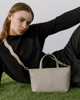 Woman lying on grass next to a handbag