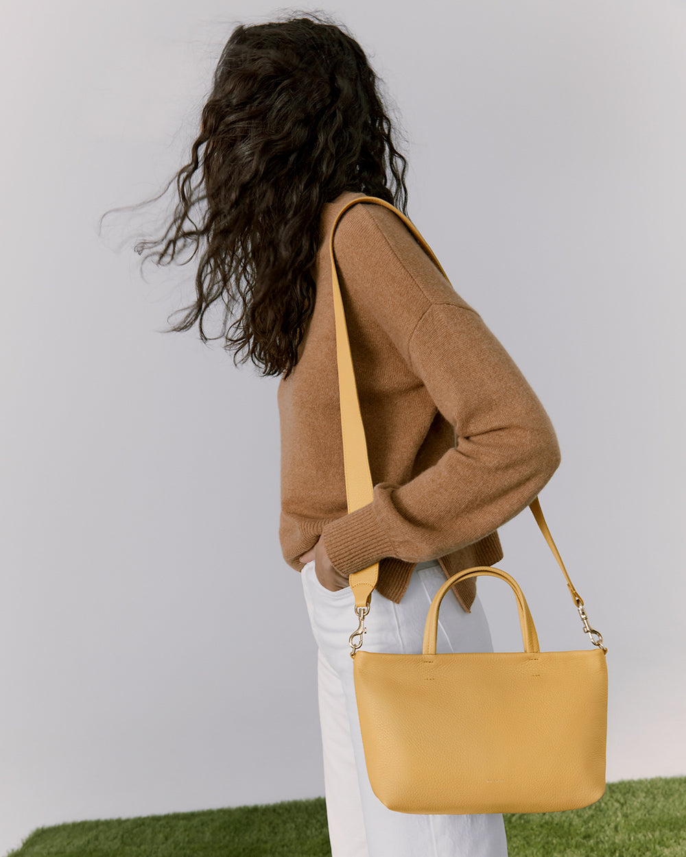 Mini Easy Zipper Tote Woman standing with her back to the camera, holding a bag over her shoulder.