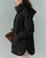 Profile view of a person wearing a quilted jacket with a high collar, holding a handbag.