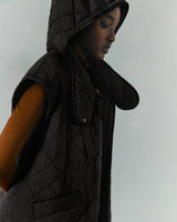 Woman in a hooded vest looking down