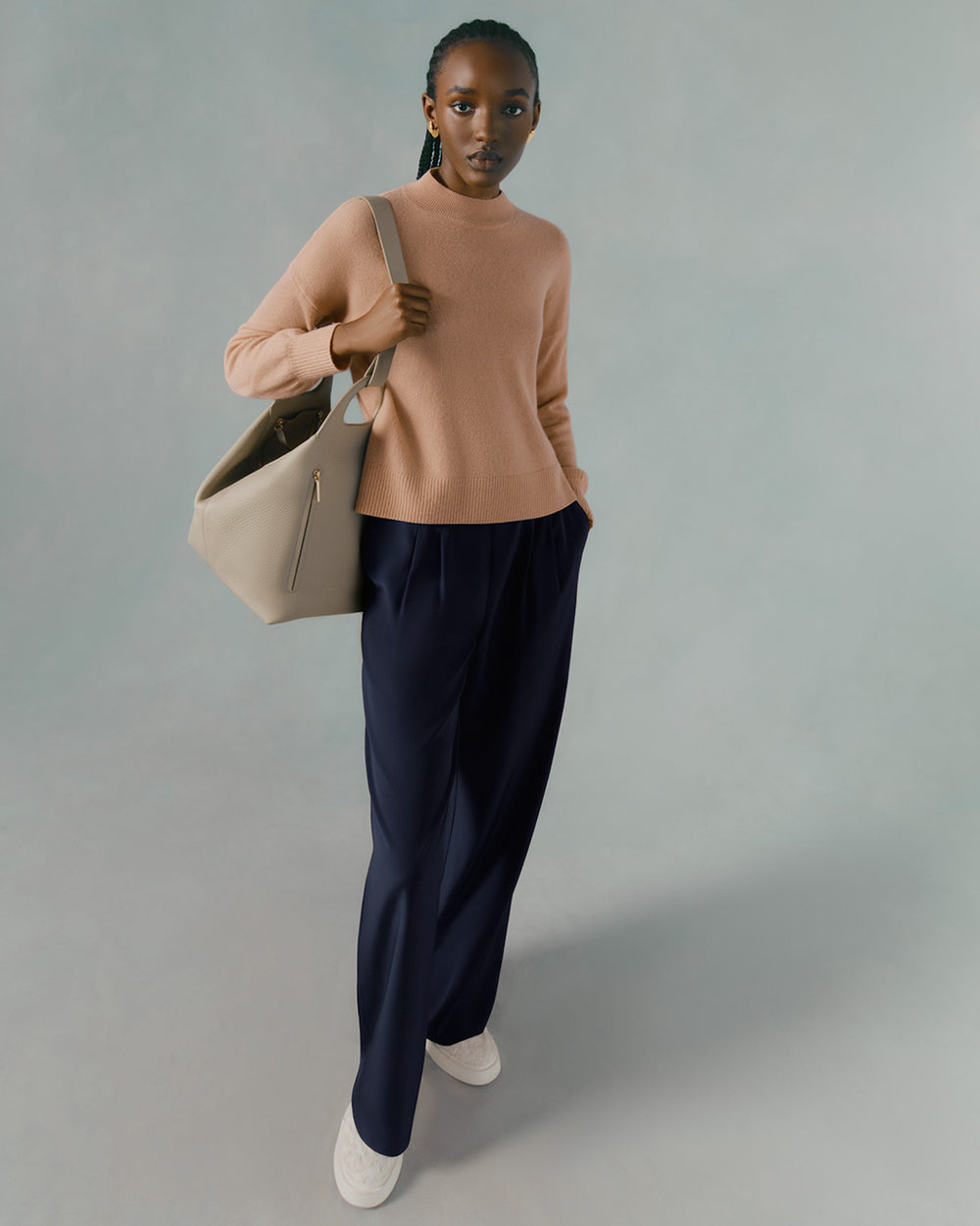 Woman walking holding a bag with a neutral expression.