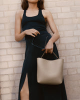 Woman standing with handbag against brick wall.