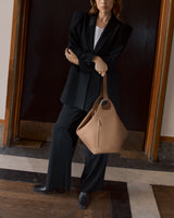 Person in suit holding a handbag standing indoors.