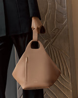 Person holding a unique handbag with a zipper pocket.