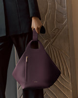 Person holding a large leather handbag with a zipper pocket.