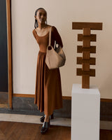 Woman in a dress stands next to a sculpture on a pedestal.