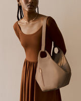 Person holding a large handbag wearing a long-sleeve dress.