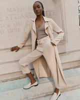 Woman posing in fashionable outfit by a stone wall