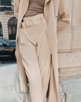 Person wearing a belt and trousers, standing by a building.