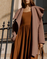 Woman in a dress and long cardigan holding a bag