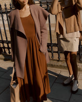 Two people standing next to a fence, wearing casual outfits and holding bags.