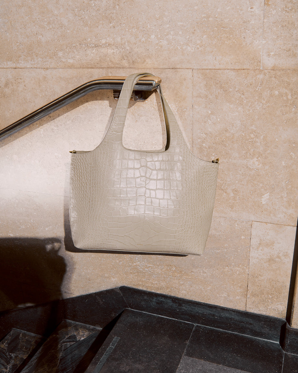 System Tote 13-inch (Croco) Handbag hanging on a railing against a tiled wall background.