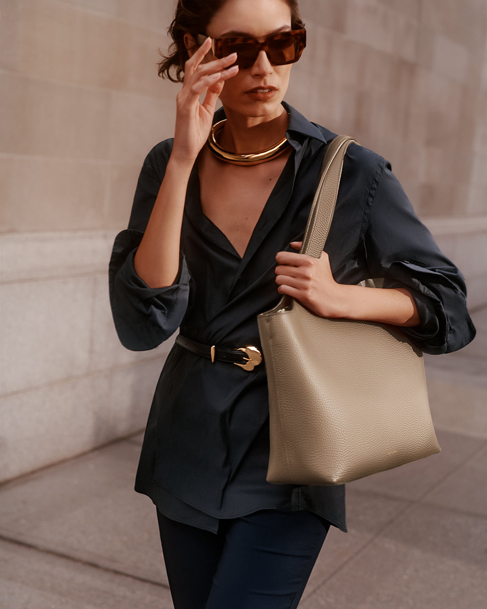 System Zipper Tote 13-inch Woman wearing sunglasses, a necklace, and a belted top, holding a shoulder bag.
