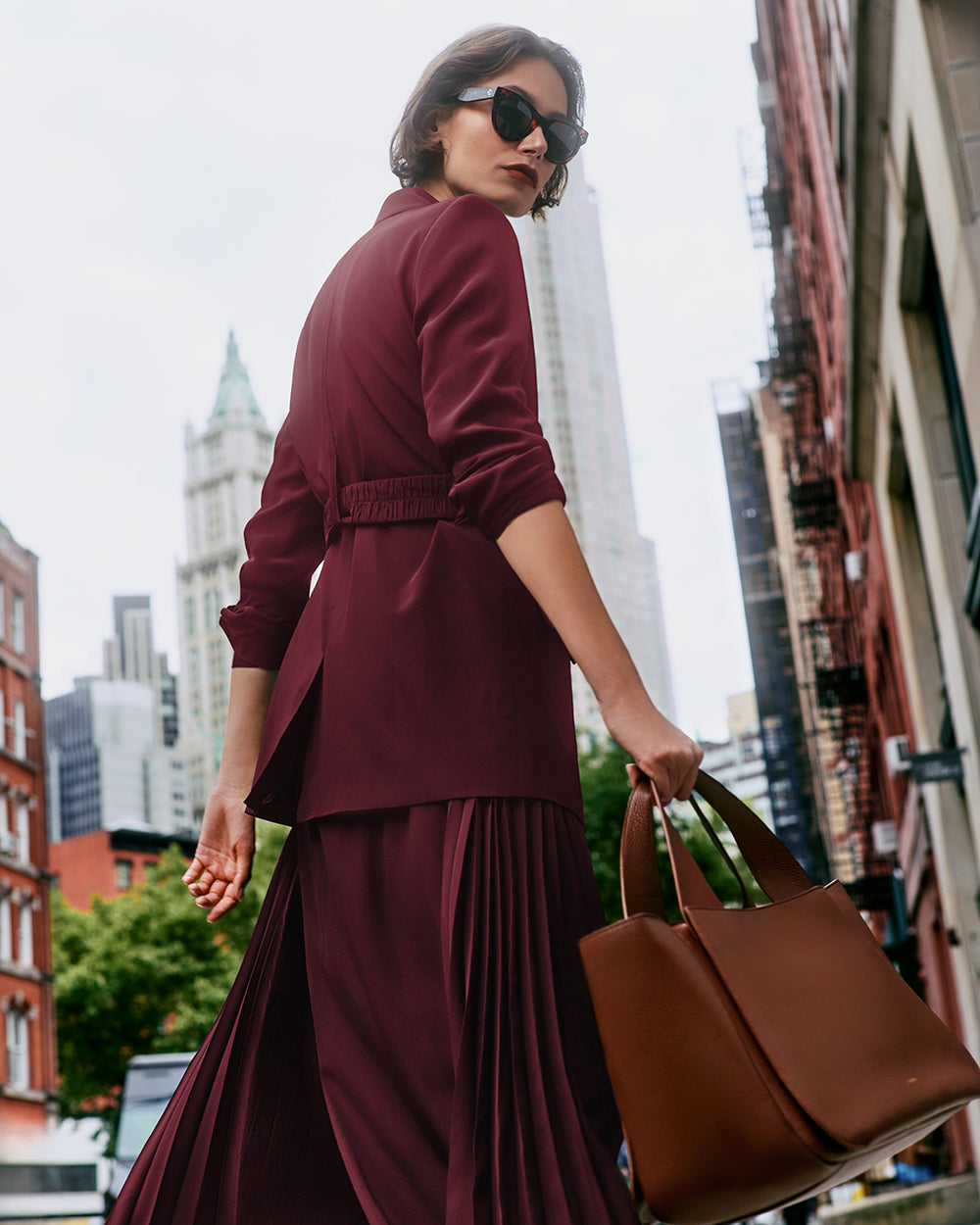 Person in red walking on a city street carrying a travel bag.