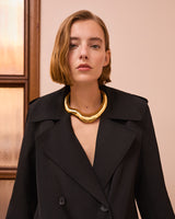 Person wearing a coat with a chunky gold necklace.