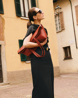 Person in dress holding large tote bag, standing outdoors near buildings.