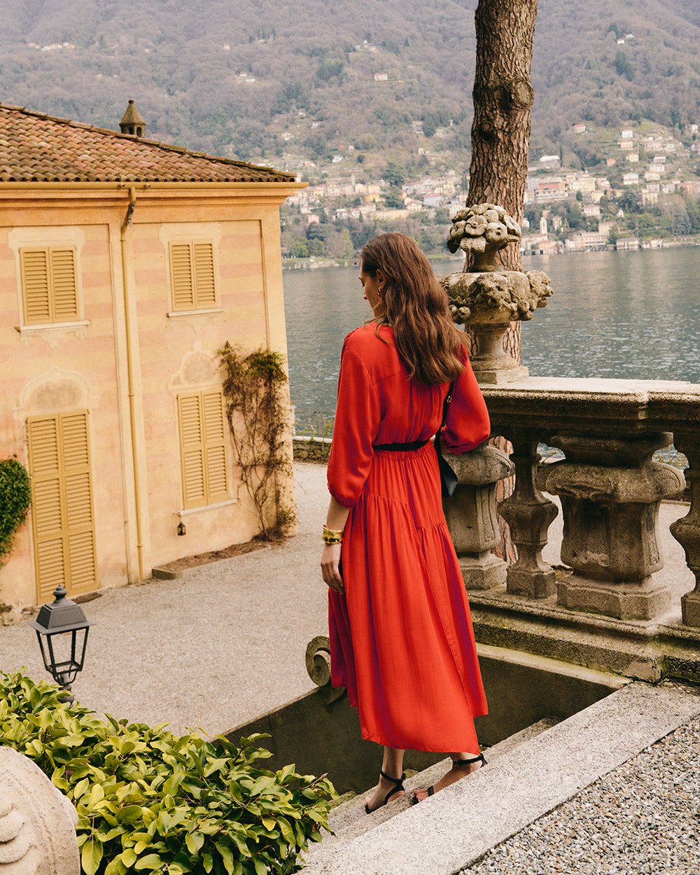 Tencel Gathered Panel Dress Woman in dress stands near railing overlooking lake and buildings in background.