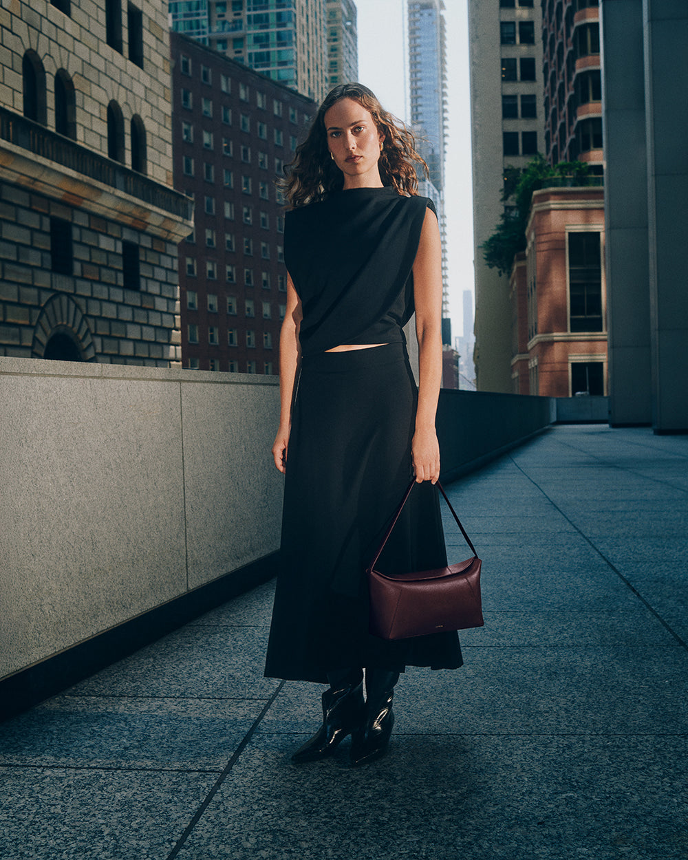 Person in a city setting wearing a long skirt and holding a handbag.