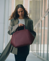 Person holding a large handbag while walking outdoors in an urban setting.