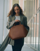 Person holding a large bag over shoulder in an urban environment.