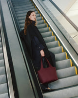Person on escalator carrying a tote bag.