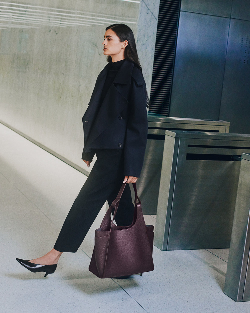 Double Loop Satchel Person walking indoors carrying a large handbag