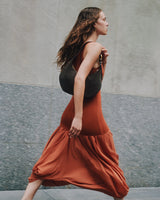 Person walking outdoors holding a handbag wearing a long dress