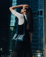 Person facing away, holding a handbag, standing near tall buildings.