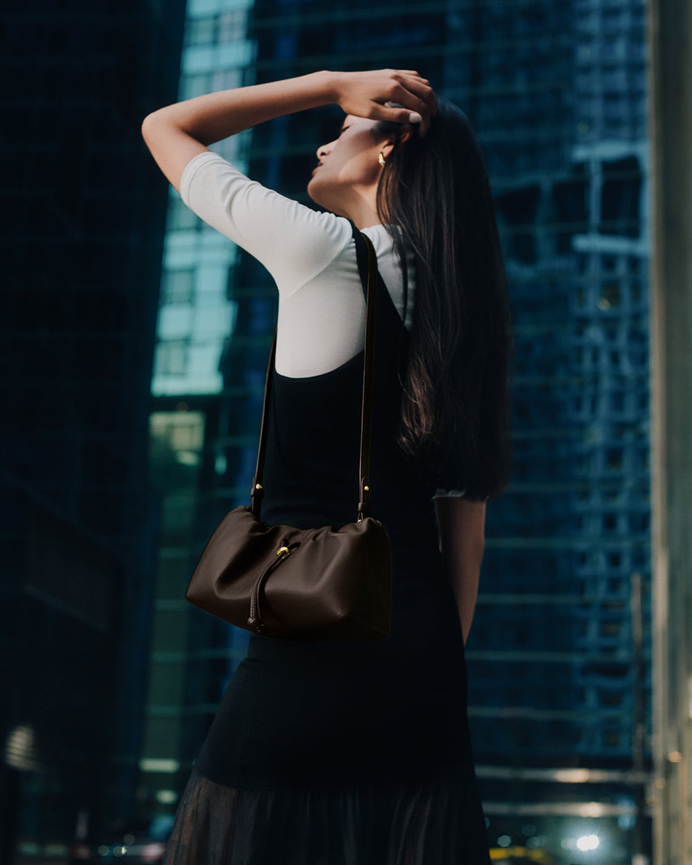 Mini Dia Bag Woman standing outdoors with handbag, looking upwards among tall buildings.