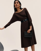 Model in dress with wide belt holding a clutch