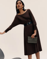 Woman in a midi dress with a belt holding a clutch