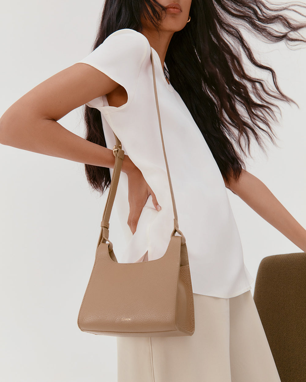 Mini Double Loop Bag Model carrying a shoulder bag wearing a short-sleeve top and pants