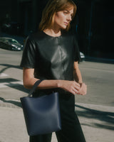 Woman holding tote bag on city street corner