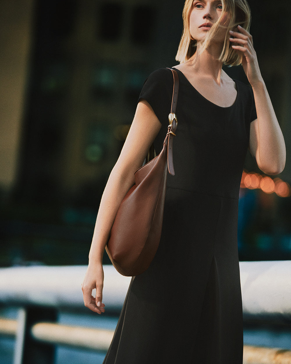 Ponte Pleated Jumpsuit Person in dress holding a shoulder bag outdoors.