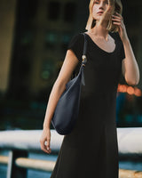 Person in a dress carrying a shoulder bag outdoors.