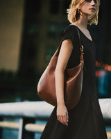 Woman in dress carrying a large shoulder bag outdoors.