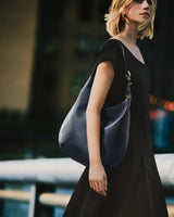 Person wearing a dress and carrying a large shoulder bag