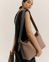 Person carrying a large shoulder bag over their left shoulder, looking back over their right shoulder