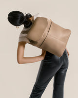 Woman with a large bag over her shoulder bending forward.