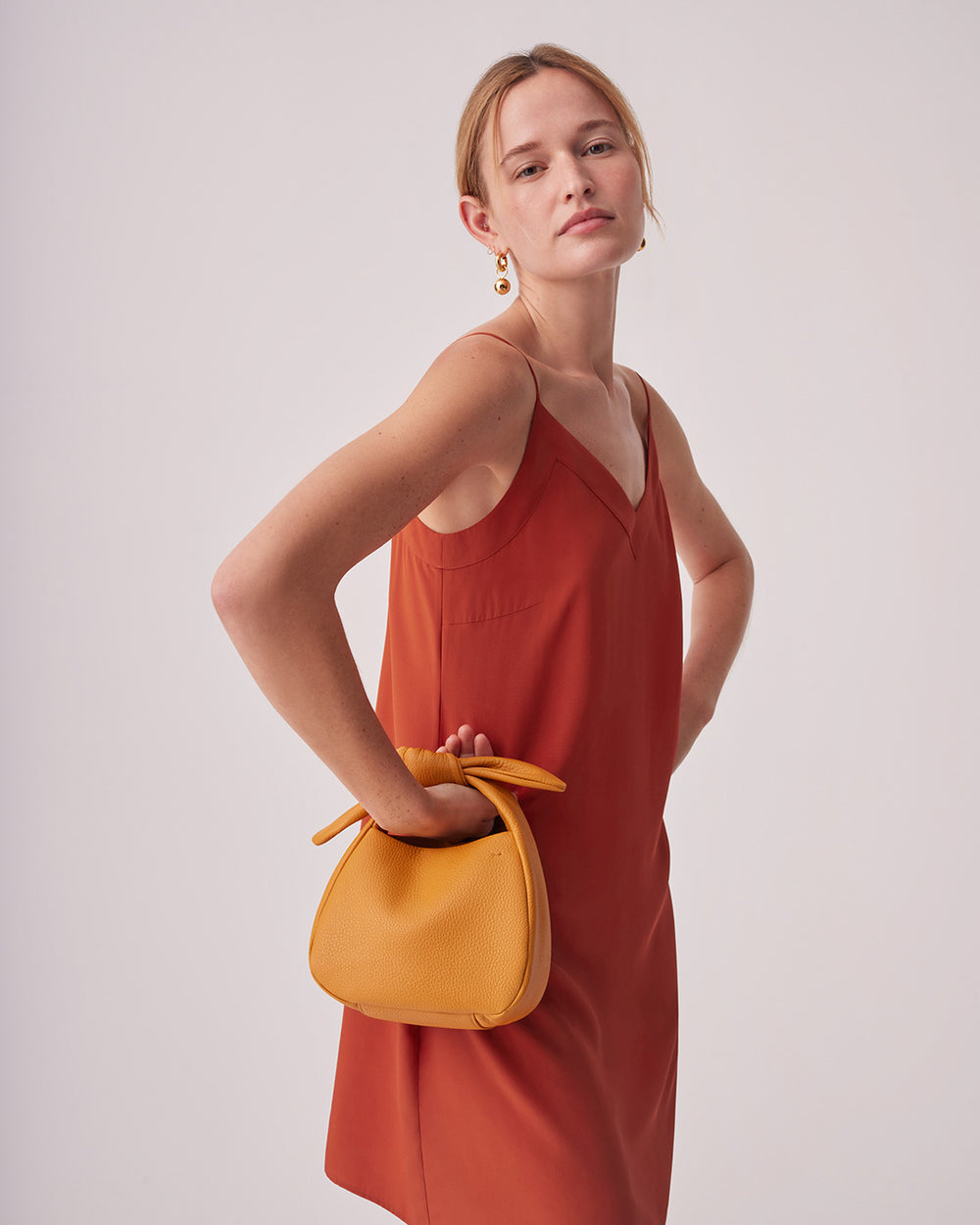 Silk Short Slip Dress Woman standing with hand on hip holding a handbag