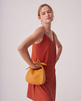 Woman standing with hand on hip holding a handbag