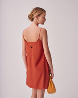 Woman in a dress looking over her shoulder, holding a handbag.