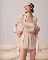 Woman in sleepwear with blazer and headband standing in a studio.